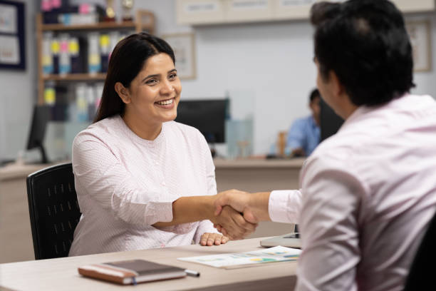 Male client handshaking with bank teller at bank counter